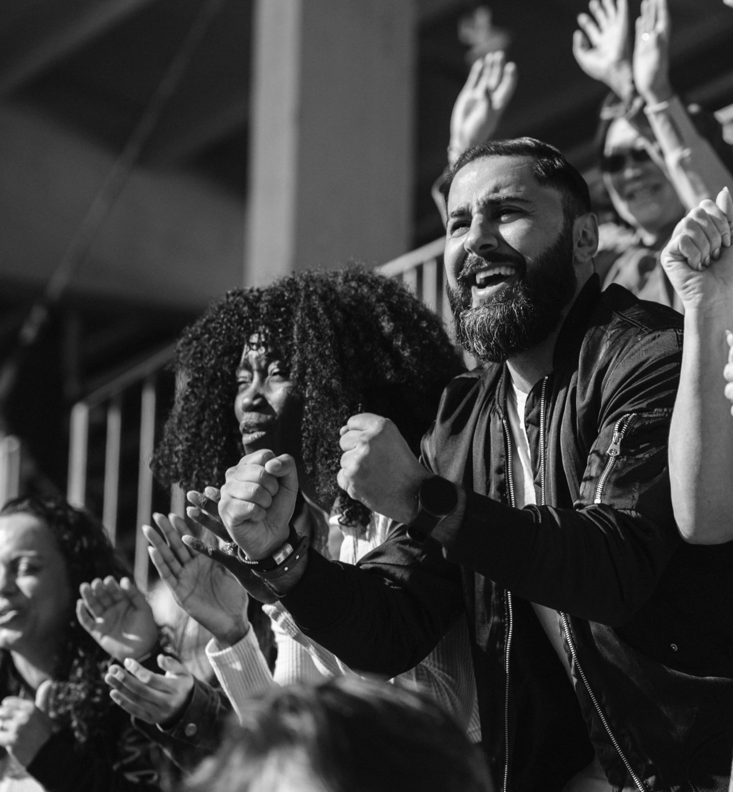 Multicultural crowd applauding and shouting in stadium bleachers on sunny match day
